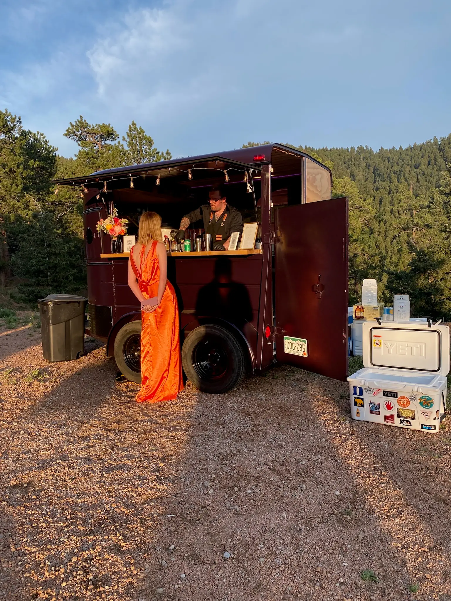The Portable Pour horse-trailer mobile bar at a mountain wedding in Woodland Park, Colorado, with a bartender serving a guest