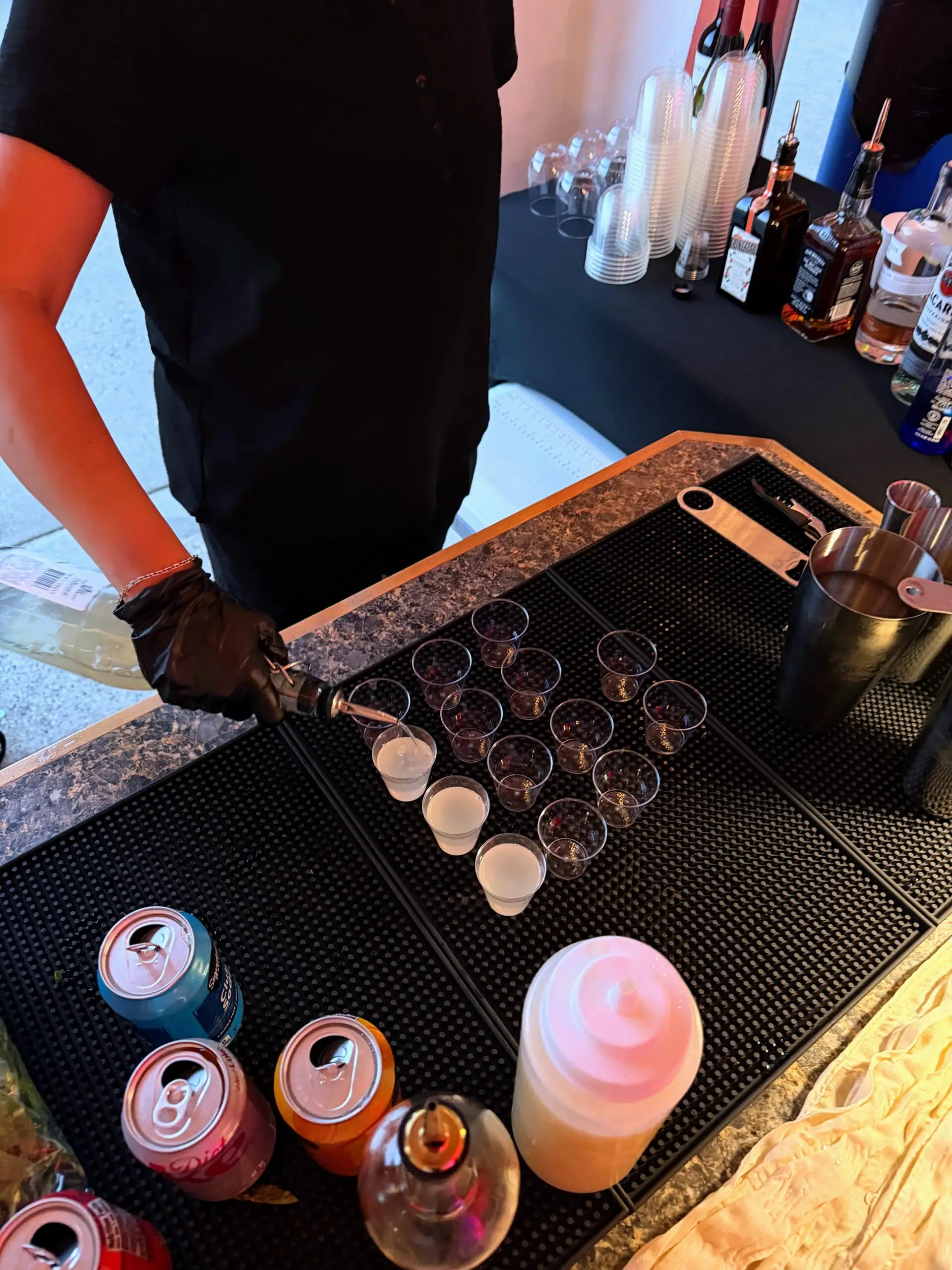 Bartender pouring shots into a lineup of small glasses on The Portable Pour bar counter